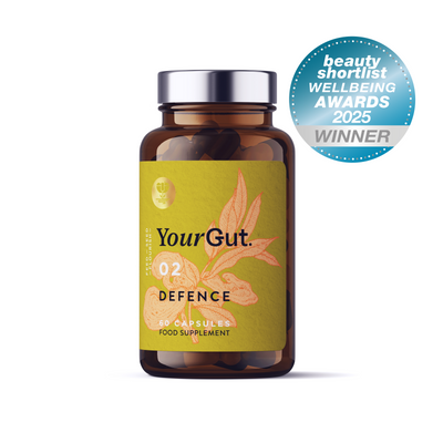 A bottle of 02 Defence immune supplement capsules with a green botanical label. A blue badge shows "beauty shortlist WELLBEING AWARDS 2025 WINNER." Promotes gut balance with its synbiotic blend of probiotics, herbs, nutrients and functional mushrooms.
