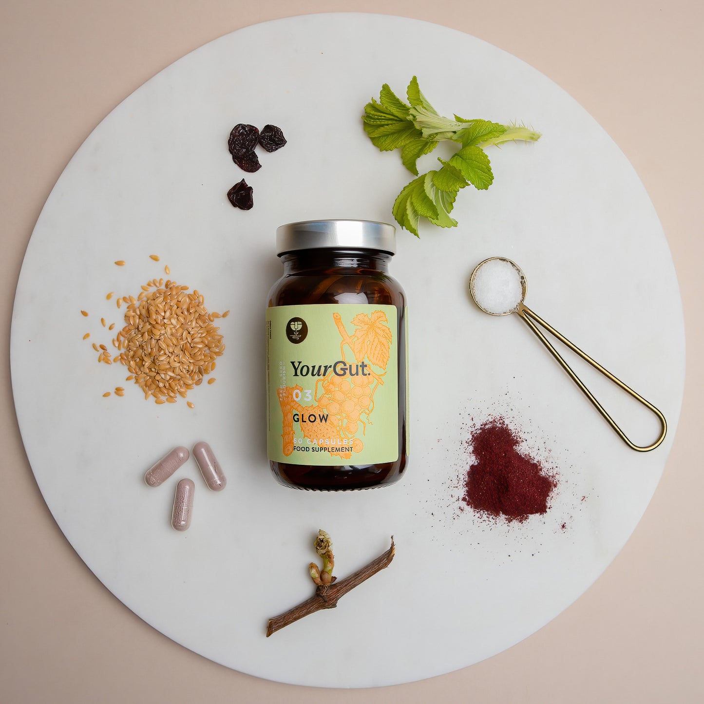 
                  
                    A bottle labeled 03 Glow sits on a round white surface, surrounded by flaxseeds, capsules, acerola cherry, rosehip, MSM, haskap, grape—highlighting this synbiotic beauty supplement for hair and wellness.
                  
                